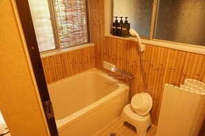 Un baño con bañera, inodoro y ventana con persianas.