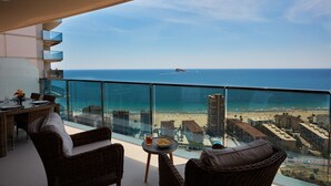 A balcony with wicker furniture, a glass table, and a clear view of the beach and ocean. - Sunset Drive Holidays Benidorm (Benidorm)