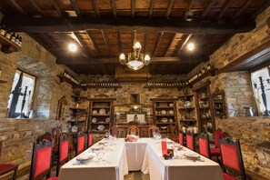 A dining room with a long table set for a meal, surrounded by stone walls and wooden beams. - Hotel Prada a Tope - Palacio de Canedo (Arganza)