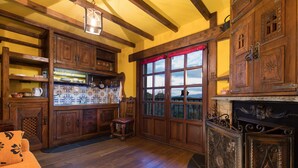 A traditional kitchen with wooden cabinets, a tiled backsplash, and a large window with a red curtain.