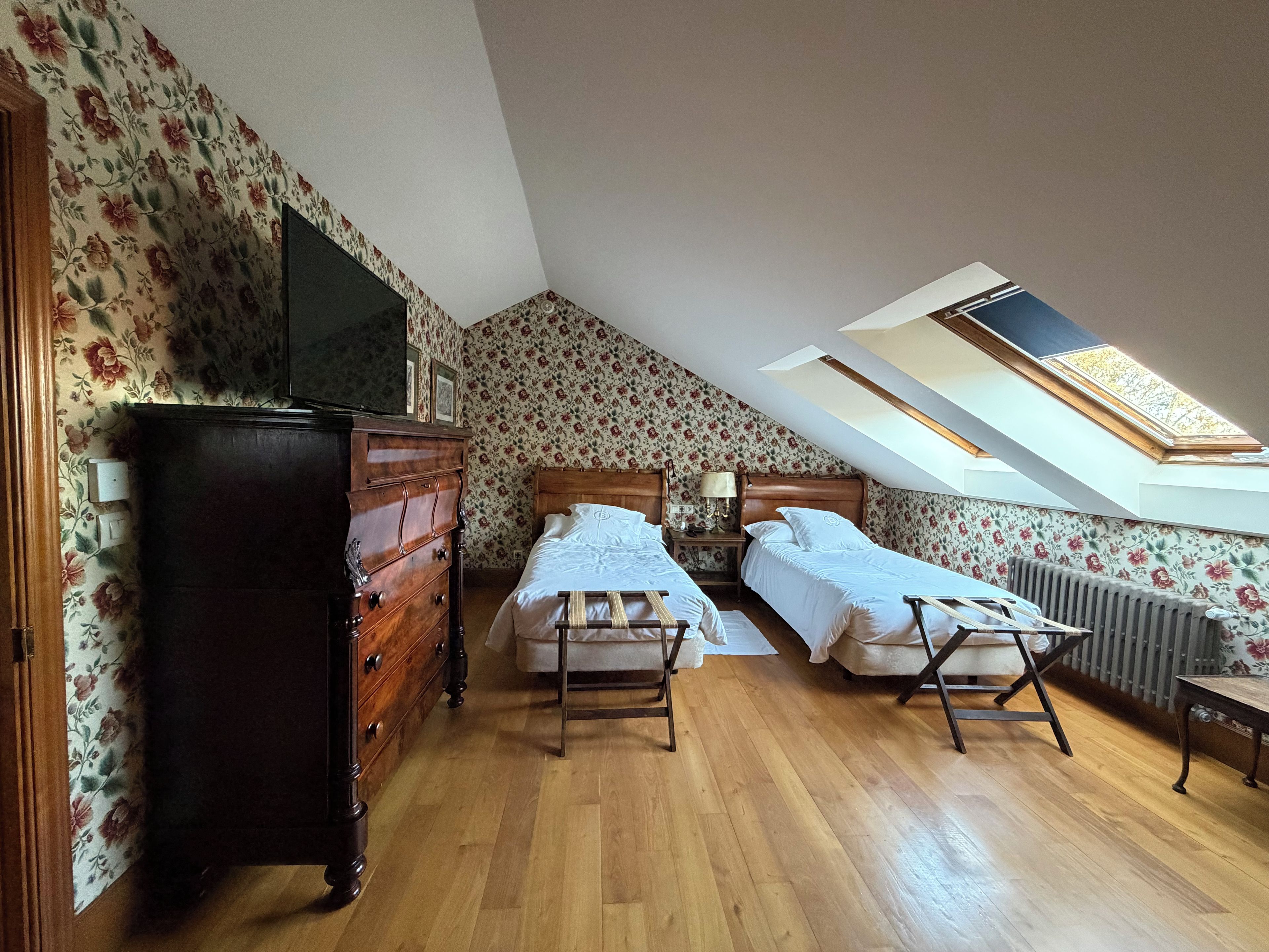 Un dormitorio con dos camas, un aparador, un radiador y un tragaluz.
