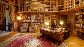 A spacious library with high wooden bookshelves, a large rug, and a desk with a lamp. - Pazo De Brandeso & Country Club (Arzua)