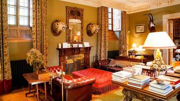 Een klassieke kamer met een open haard, lederen meubels en een boekenplank vol boeken.