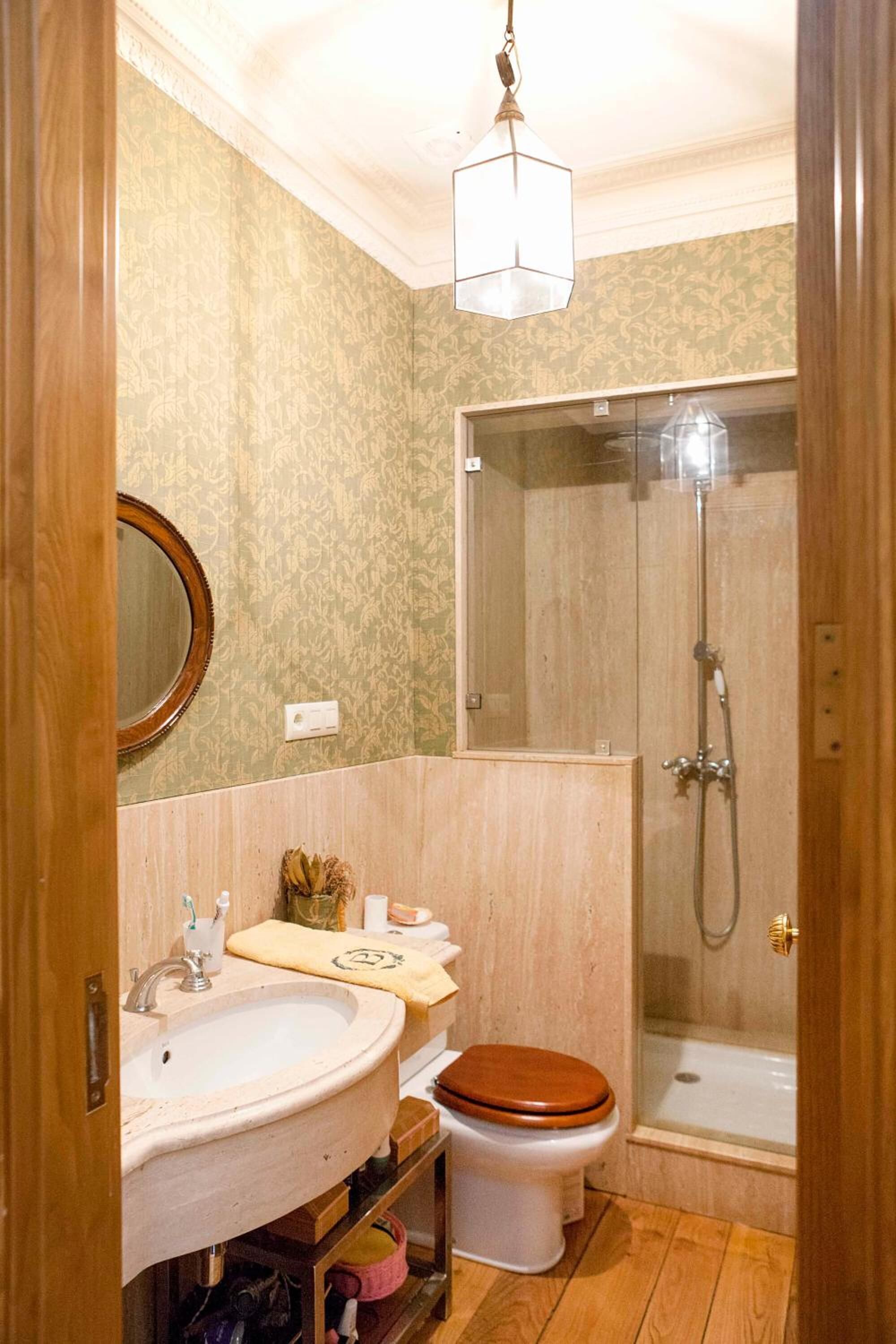 A bathroom with a wooden vanity, a sink, a toilet, and a glass-enclosed shower.