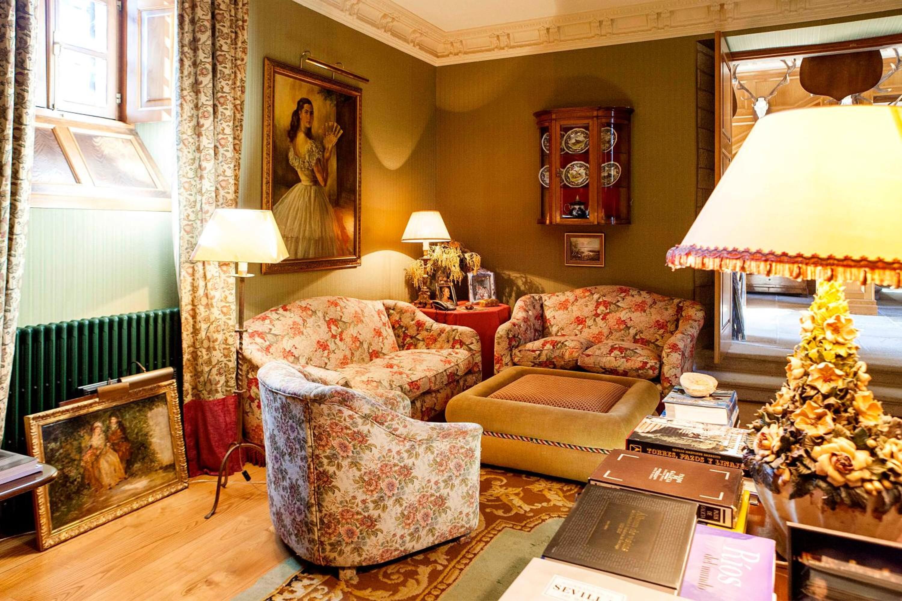 Un salon chaleureux avec des fauteuils à motifs floraux, un meuble en bois et un tableau encadré accroché au mur.