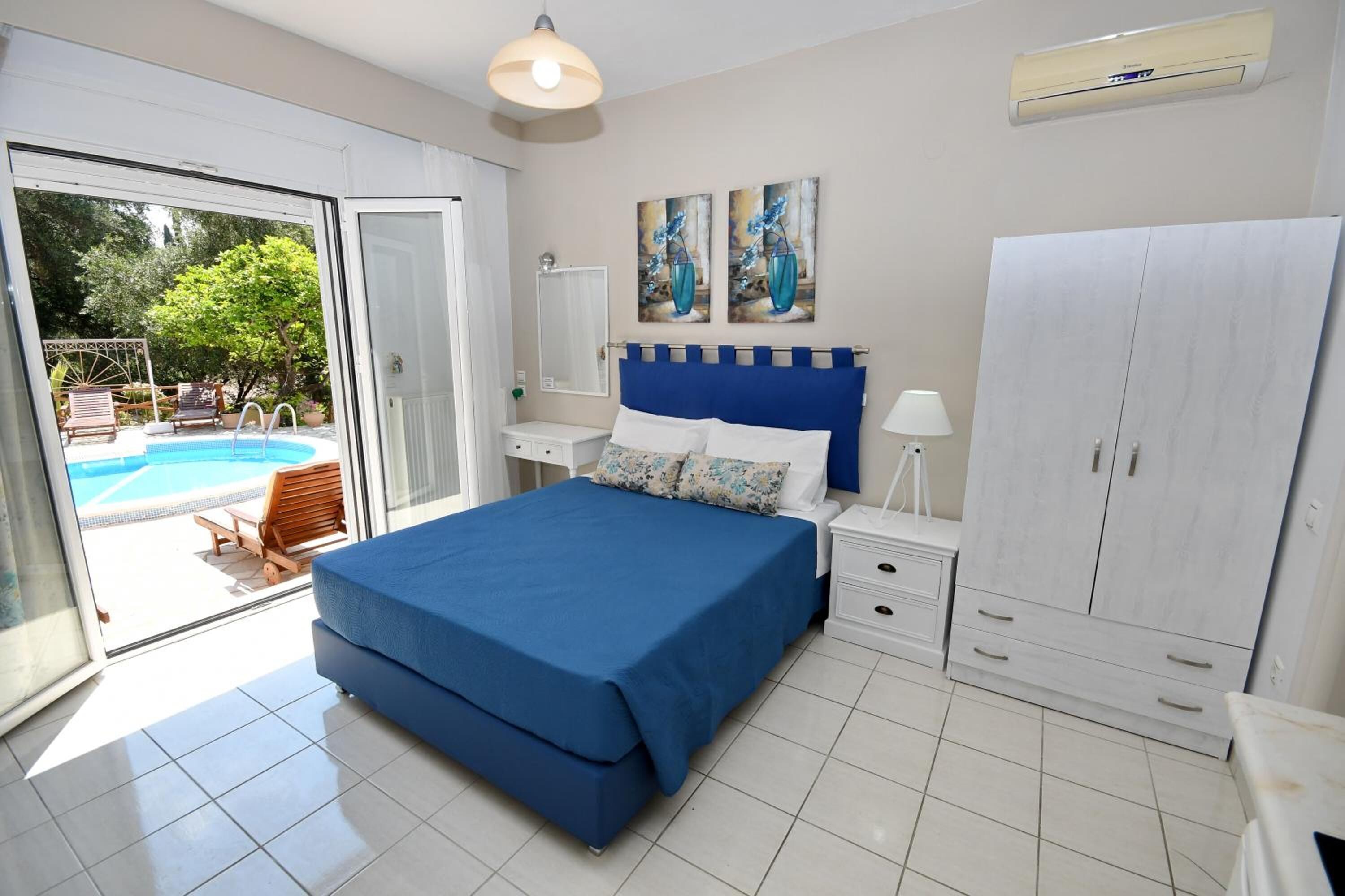 A bedroom with a large bed, a wardrobe, a nightstand, and a view of a swimming pool.