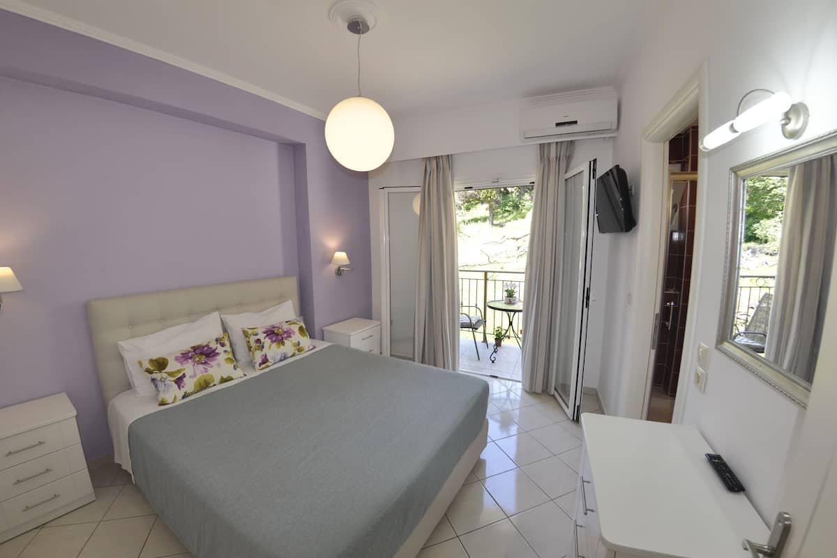A bedroom with a bed, bedside tables, a desk, and a TV.