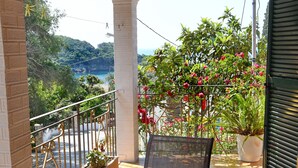A balcony with a round glass table, a chair, and a potted plant. - Angels Pool Bar (Corfu)
