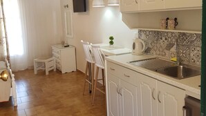 A kitchen with white cabinets, a sink, and a small table with chairs. - Angels Pool Bar (Corfu)