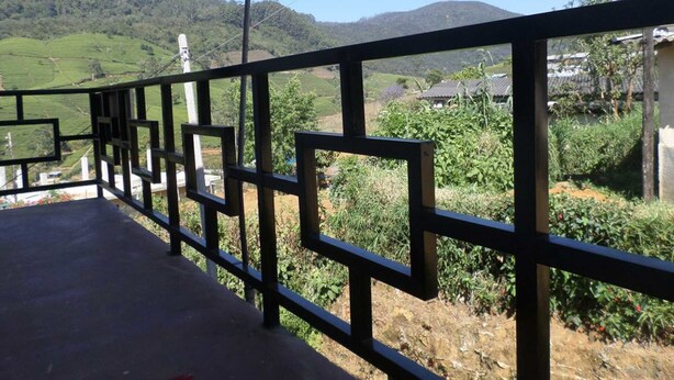 A rural road with a metal fence, greenery, and distant houses. - Yoho The Train View (Nanuoya)