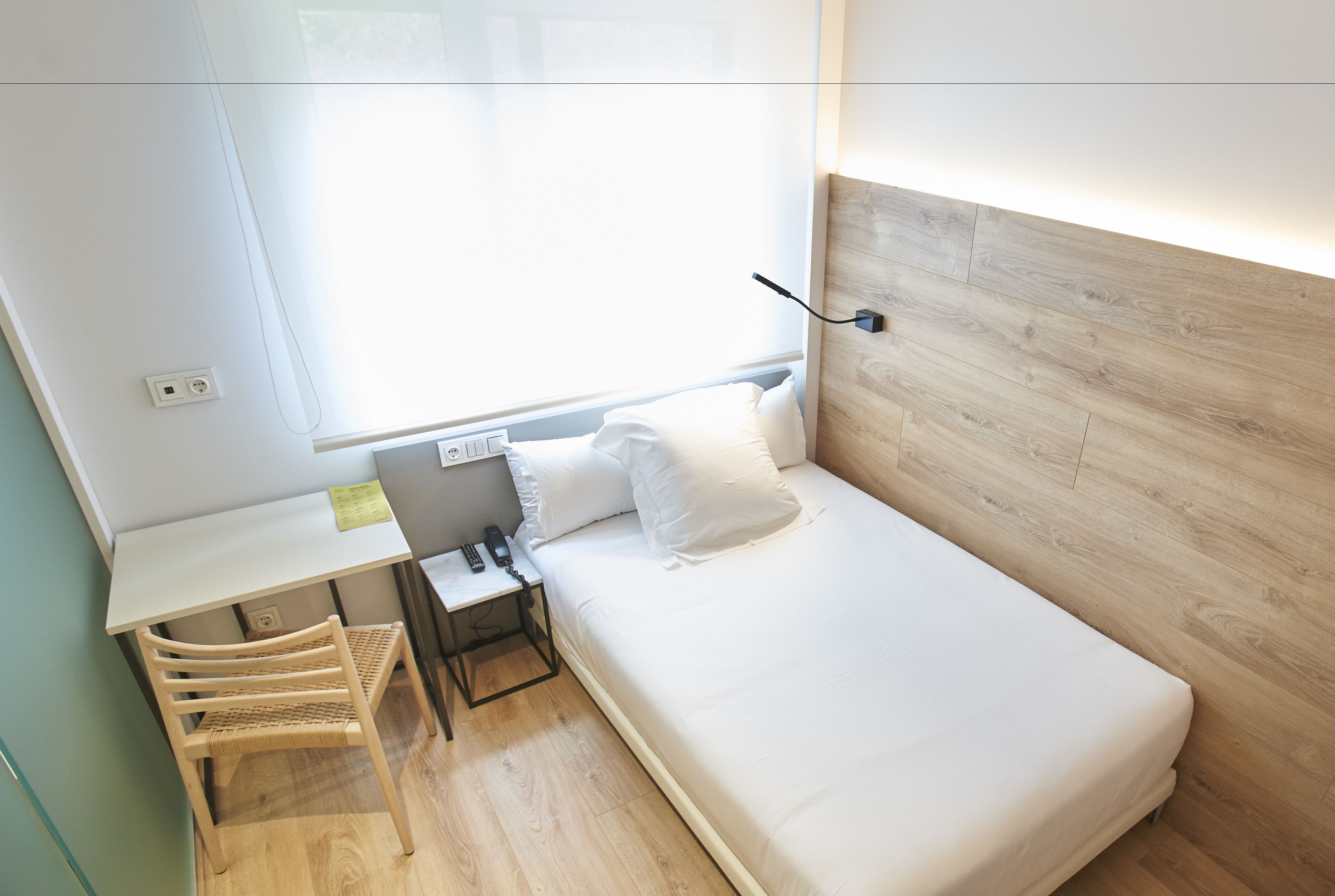 Ein kleines Zimmer mit einem Bett, einem Schreibtisch und einem Stuhl.
