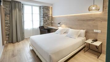 Una camera d'albergo moderna con un letto grande, una scrivania e una sedia.