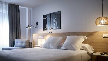 A hotel room with a large bed, two bedside tables, a wall-mounted lamp, and a ceiling light fixture.