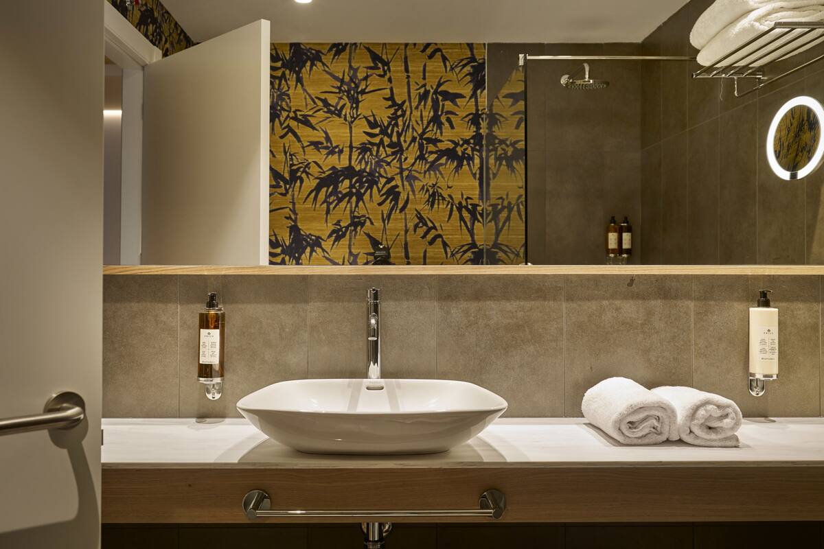 A bathroom with a large vessel sink, a mirror, and a towel rack.