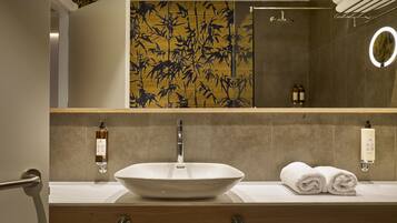 Une salle de bain avec un grand lavabo sur colonne, un miroir et un porte-serviettes.