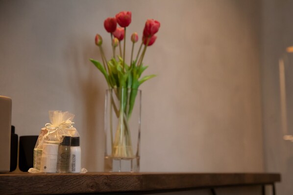 A wooden table with a vase of red tulips and a gift wrapped in clear plastic.