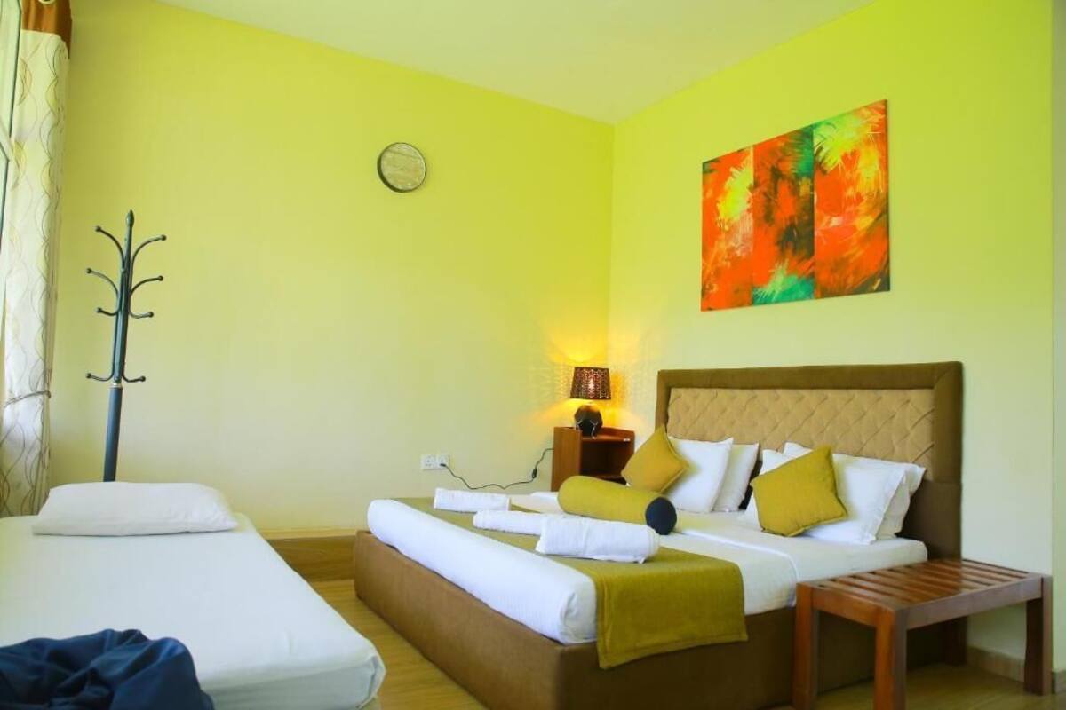 A hotel room with a bed, a bedside table, a lamp, and a painting on the wall.