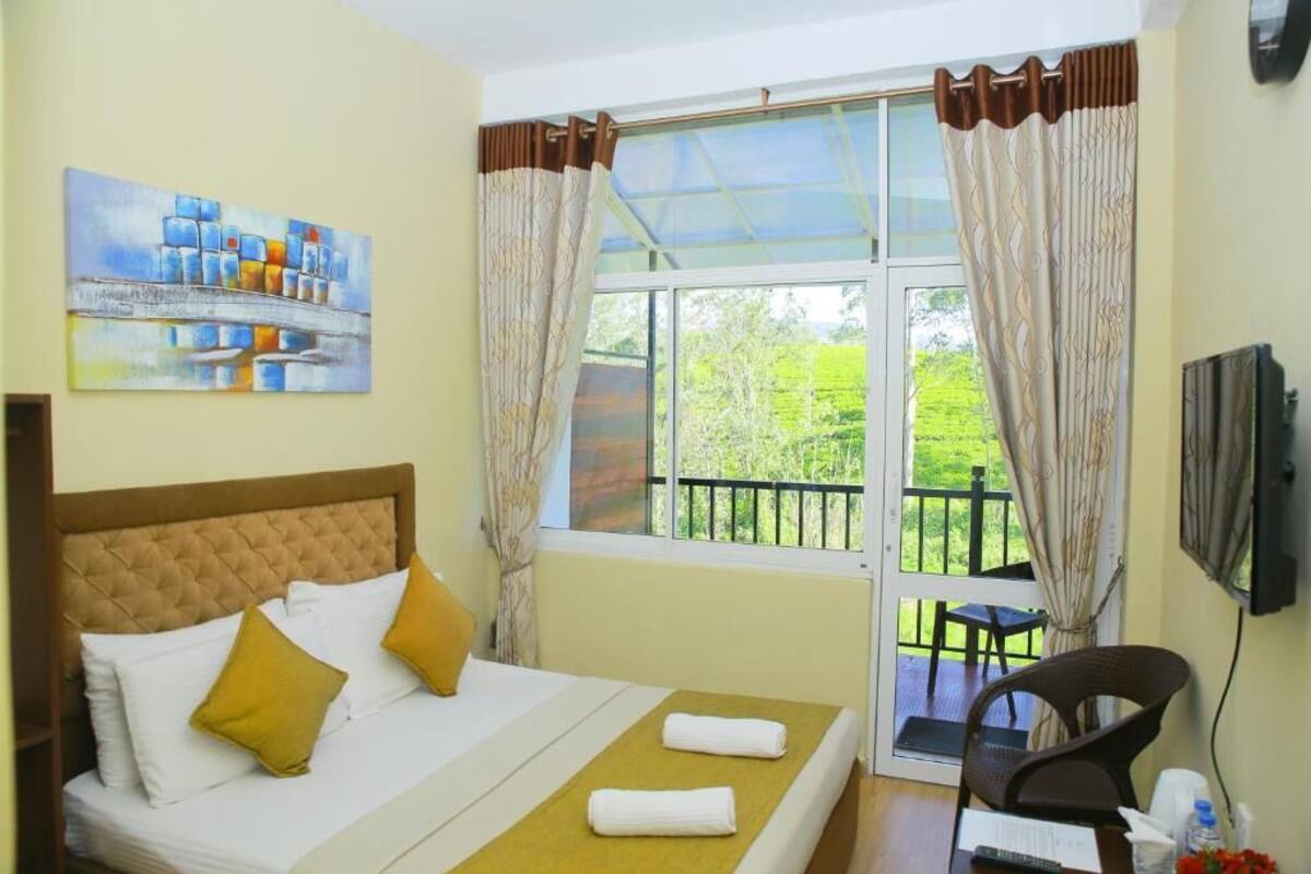 A hotel room with a bed, a chair, a TV, and a window with curtains.