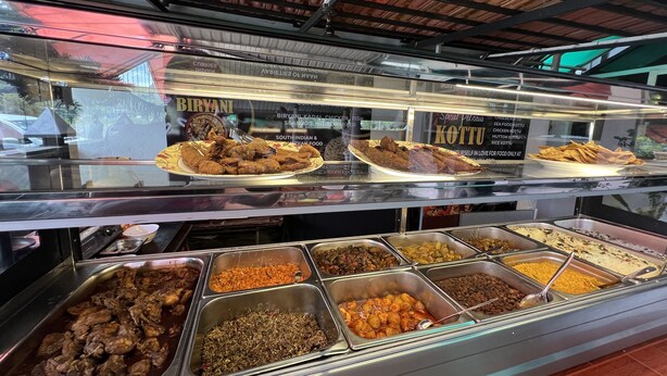 Un bufé con diversos platos, incluyendo biryani, kottu y otras opciones de comida india y del sur de la India.