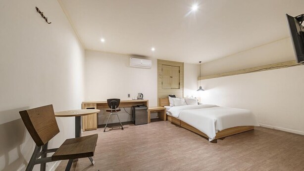 Una habitación de hotel moderna con una cama, escritorio, silla y una mesita.