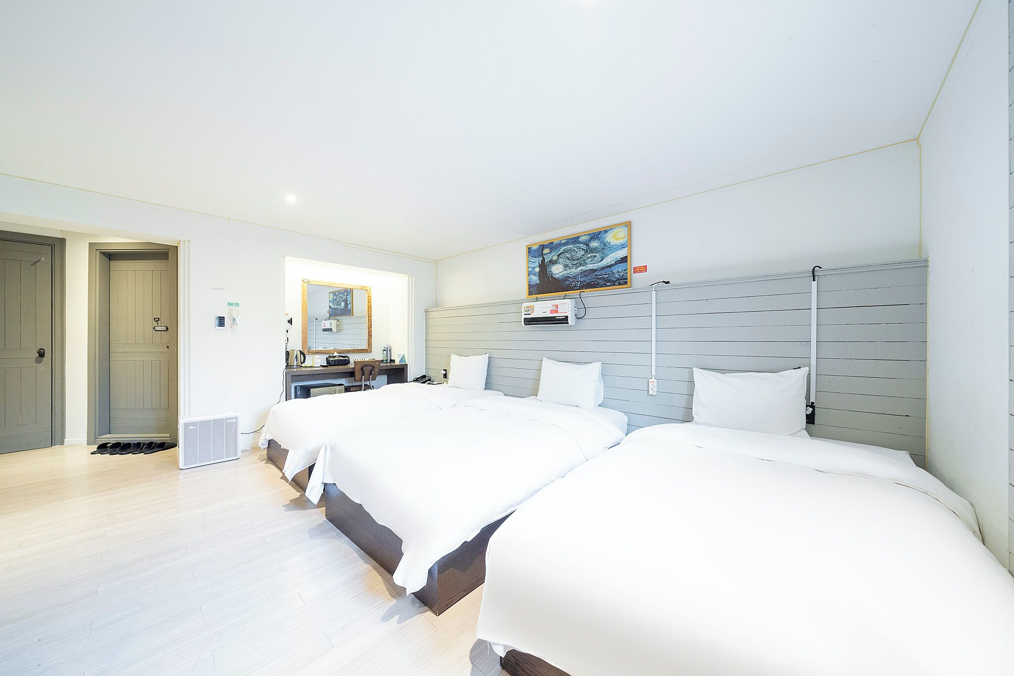 Quarto de hotel com duas camas, uma escrivaninha, uma cadeira e um quadro na parede.