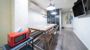 Una cocina moderna con microondas, una mesa, sillas y un televisor montado en la pared.