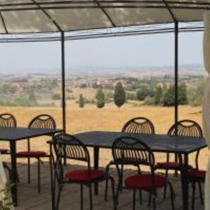 Une terrasse extérieure avec des tables et des chaises, offrant une vue sur un paysage rural.