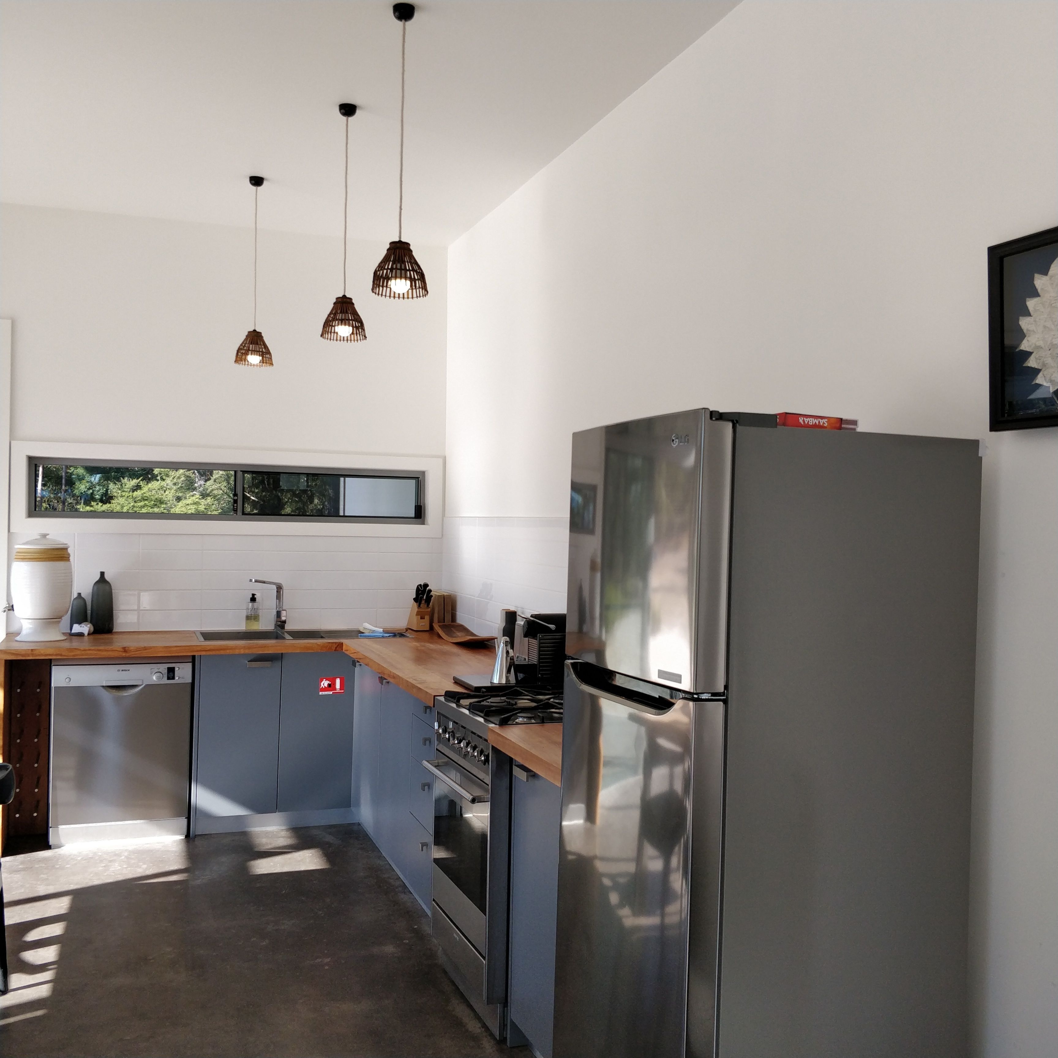 A modern kitchen with stainless steel appliances, a wooden countertop, and pendant lighting.
