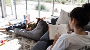 A person reading a book on a couch with a window view. - Aplite House (Friendly Beaches)