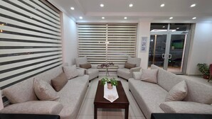 A modern living room with two sofas, a coffee table, and a large window with blinds. - Konuk Hotel (Gerede)