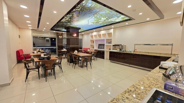 A modern hotel lobby with a large digital ceiling display, a reception desk, and a seating area with tables and chairs. - Konuk Hotel (Gerede)