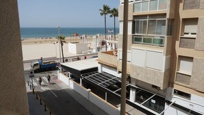 A building with a view of the beach, palm trees, and a truck parked on the street. - Hospederia Imar (Cádiz)