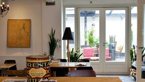 A dining area with a wooden table, chairs, and a large window with a view of the outside. - Hello I'm Local (Haarlem)