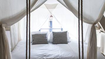 A bed with a canopy, a hanging swing, and a view of the outdoors.