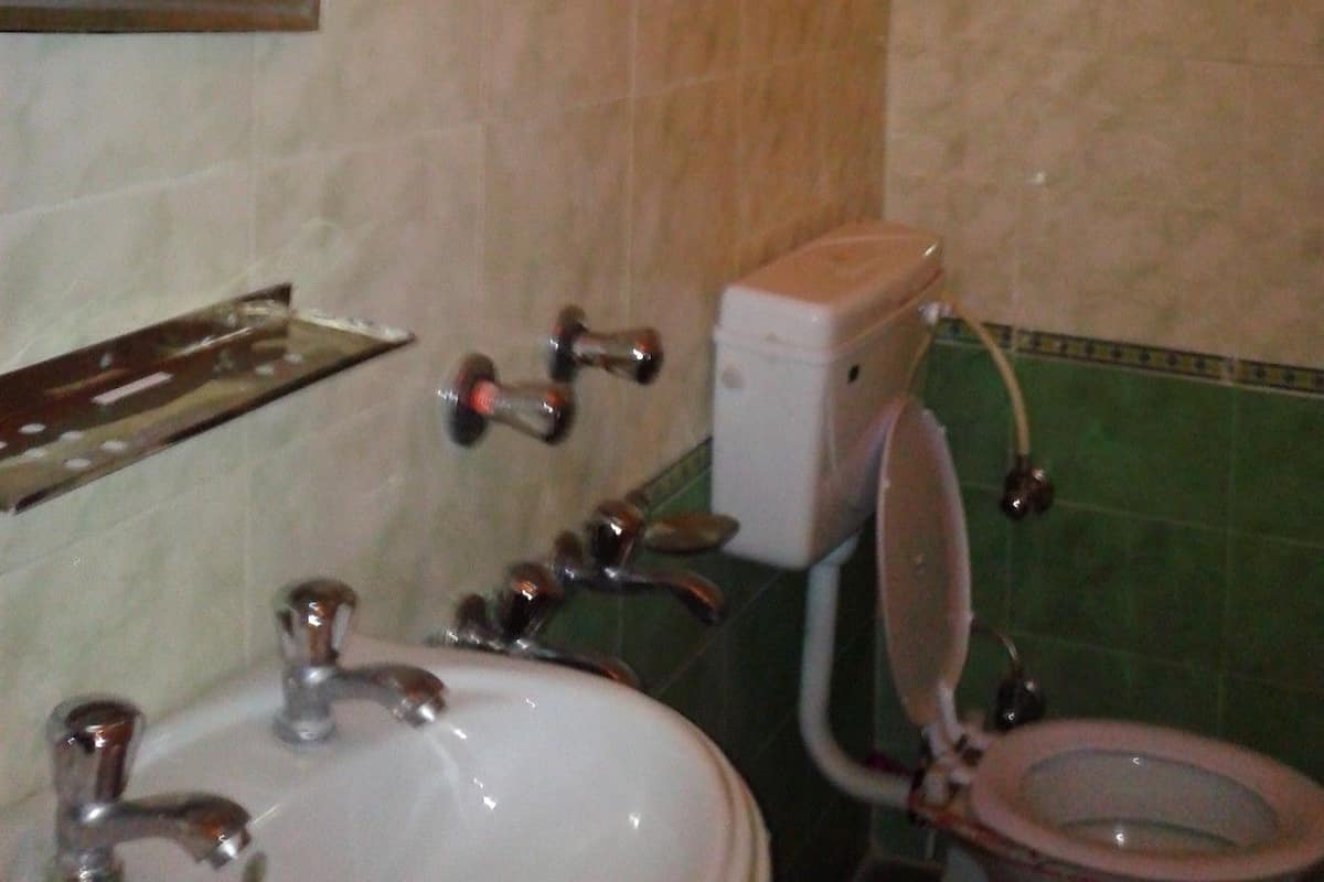 A bathroom with a sink, mirror, toilet, and a hand dryer.