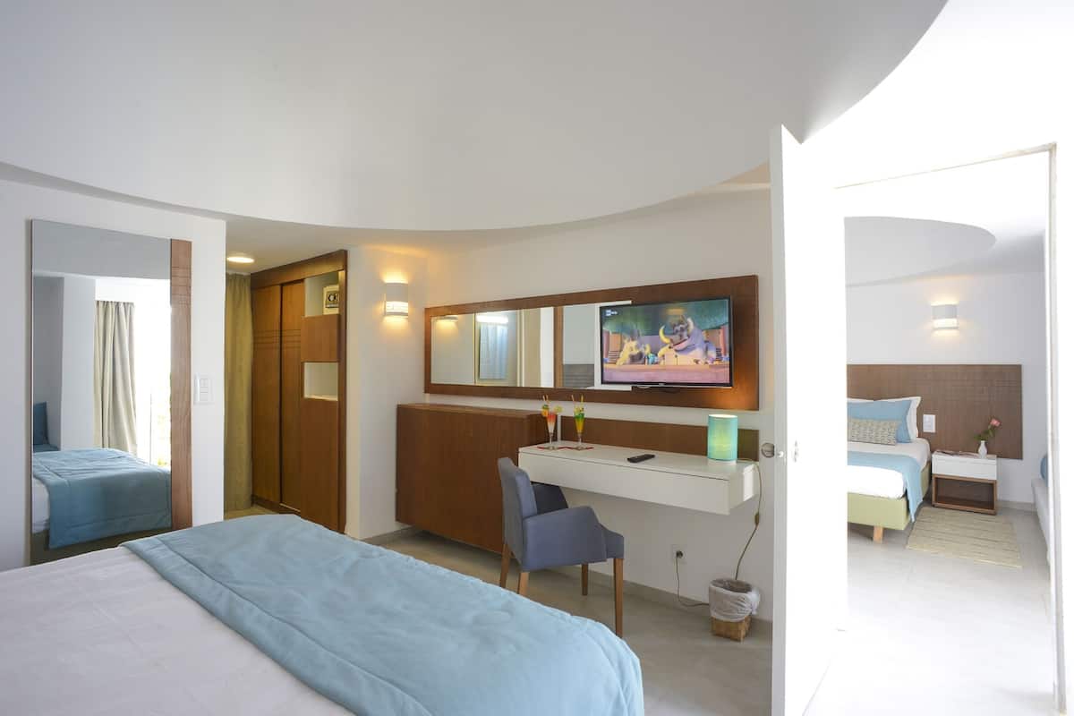 A hotel room with a bed, a desk, a chair, a television, and a bathroom.