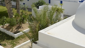 Un complexe hôtelier aux bâtiments blancs et aux toits en forme de dôme, entouré de palmiers et de verdure.