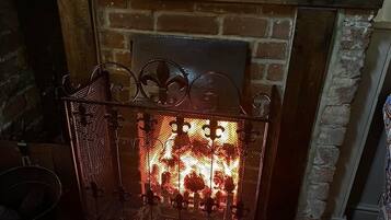 Una chimenea con una protección metálica y un muro de ladrillo al fondo.