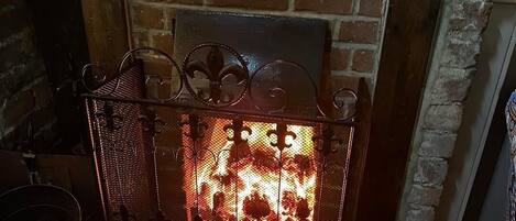 A fireplace with a metal screen and a brick wall behind it.
