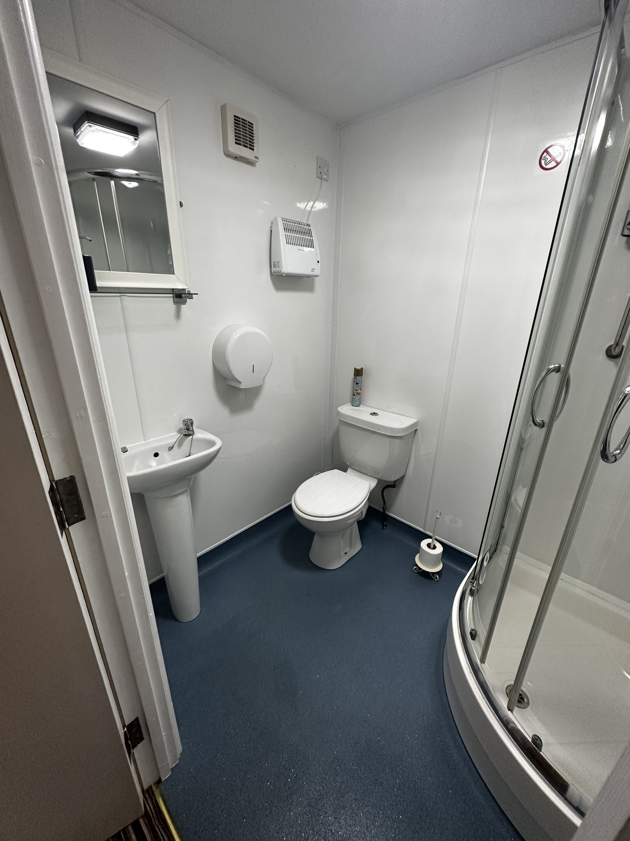 A small, compact bathroom with a toilet, sink, and shower.