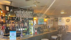 En bar med skranke, barstole samt diverse flasker og glas.