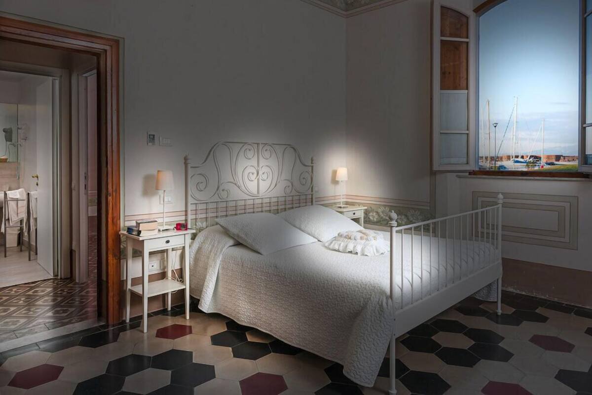 A neatly arranged bedroom with a white bed, a bedside table, and a nightstand.