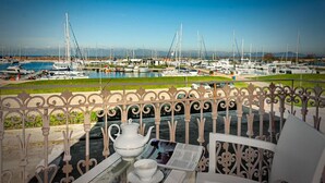 A balcony with a table set for tea, overlooking a marina with boats. - Villino Ermione (Pisa)