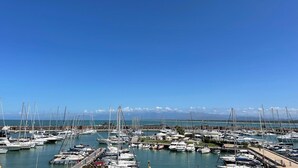 A marina with numerous boats docked, a clear sky, and a distant mountain range. - Villino Ermione (Pisa)