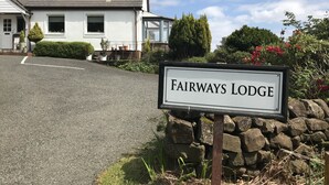A sign for Fairways Lodge with a stone wall and greenery in the background. - Fairways Lodge B&B (Isle of Mull)