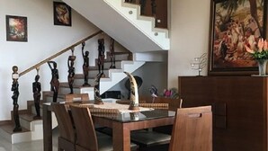 A dining area with a wooden table and chairs, a staircase with a railing, and a hanging light fixture. - Nice view Apartment (Chnaneir)