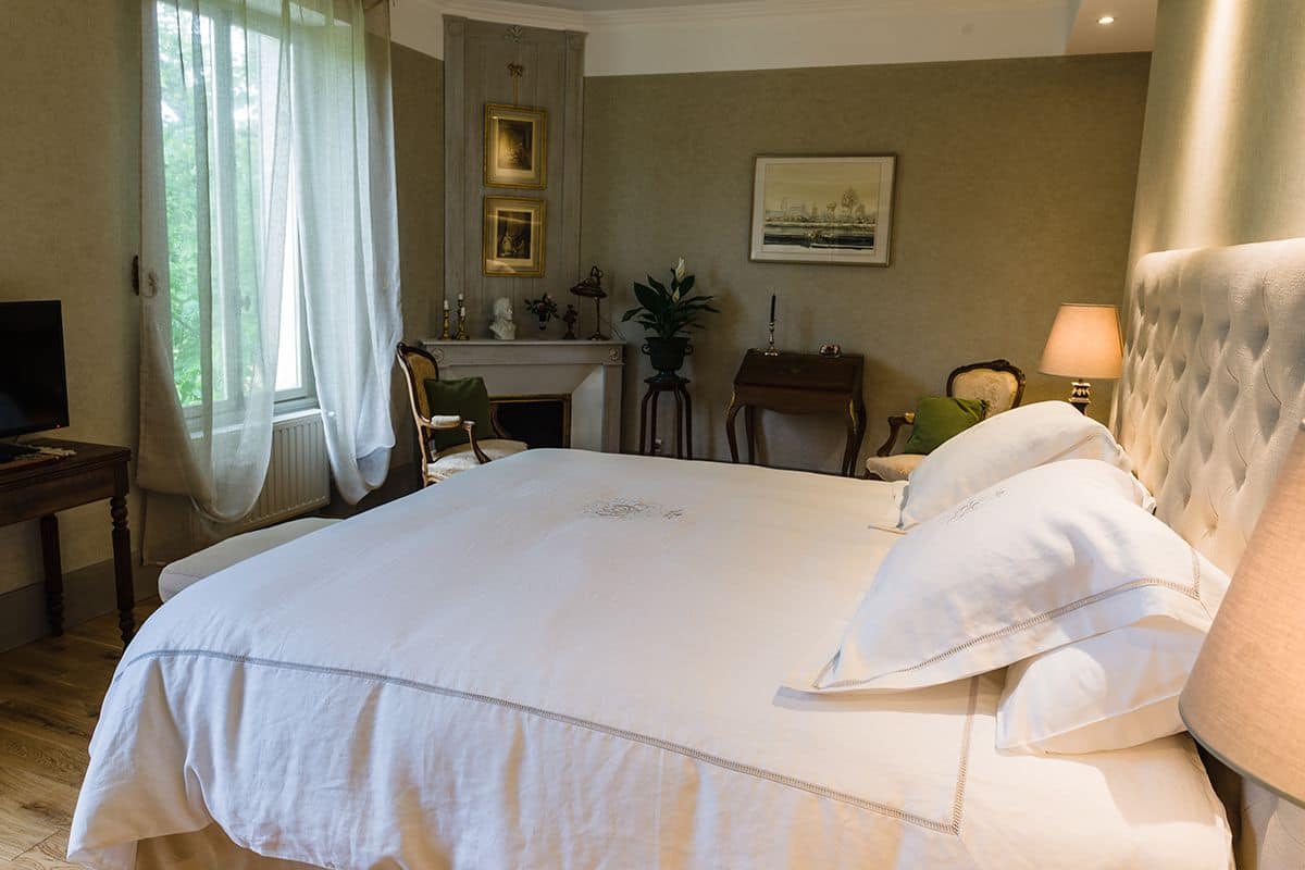A hotel room with a large bed, a fireplace, a desk, and a television.