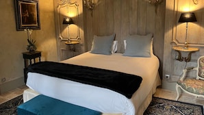 A bedroom with a large bed, two bedside lamps, a framed picture, and a small table with a vase. - Château de Saint Georges (Saint-Georges-sur-Moulon)