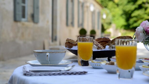 A breakfast setup with croissants, orange juice, and a cup on a table outdoors. - Château de Saint Georges (Saint-Georges-sur-Moulon)