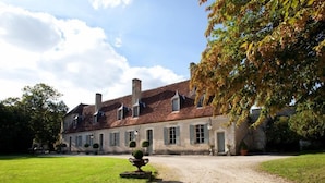 A large, historic building with a symmetrical facade, multiple chimneys, and a gravel driveway leading to a gated entrance. - Château de Saint Georges (Saint-Georges-sur-Moulon)